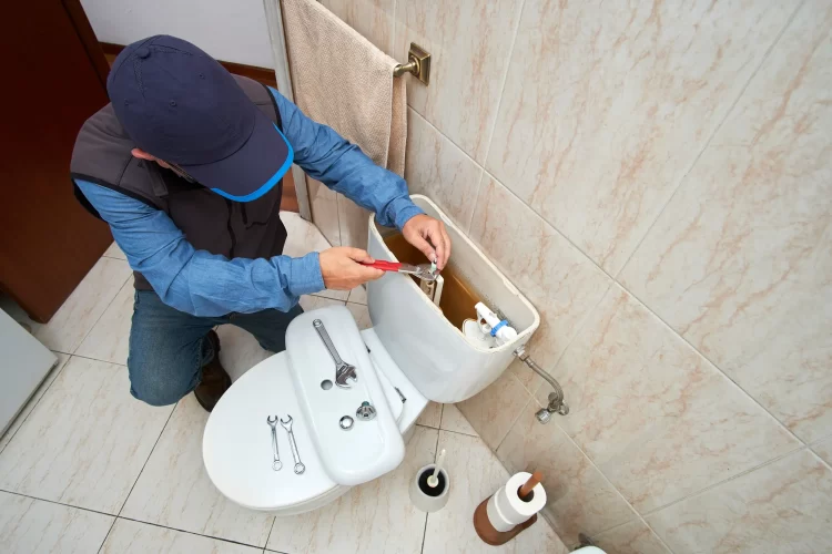 plumber fixing the toilet water tank refill.