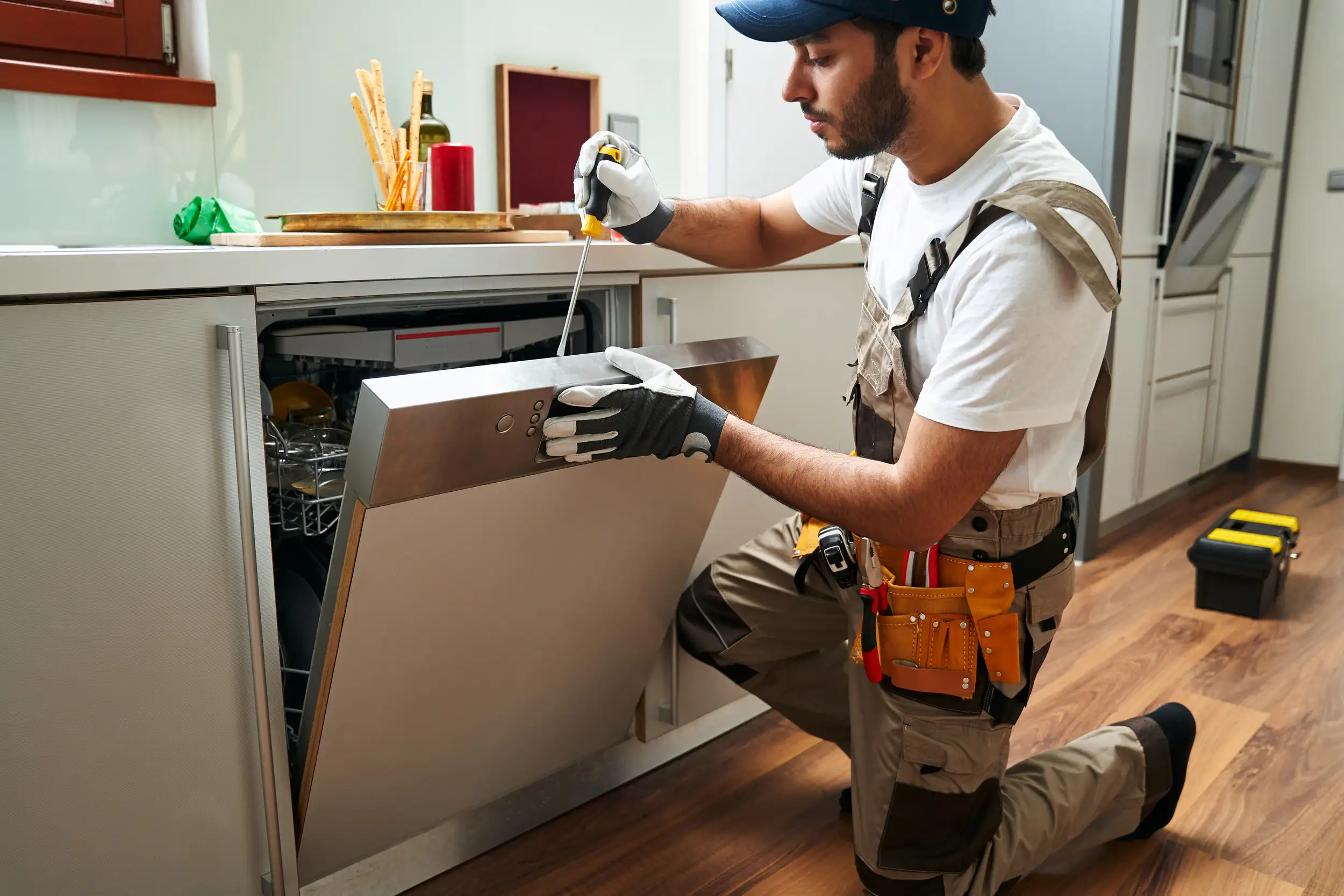 A professional service worker repairing the dishwasher.